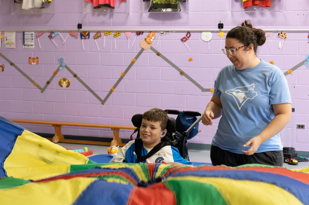 Child in wheelchair holding colourful parachute