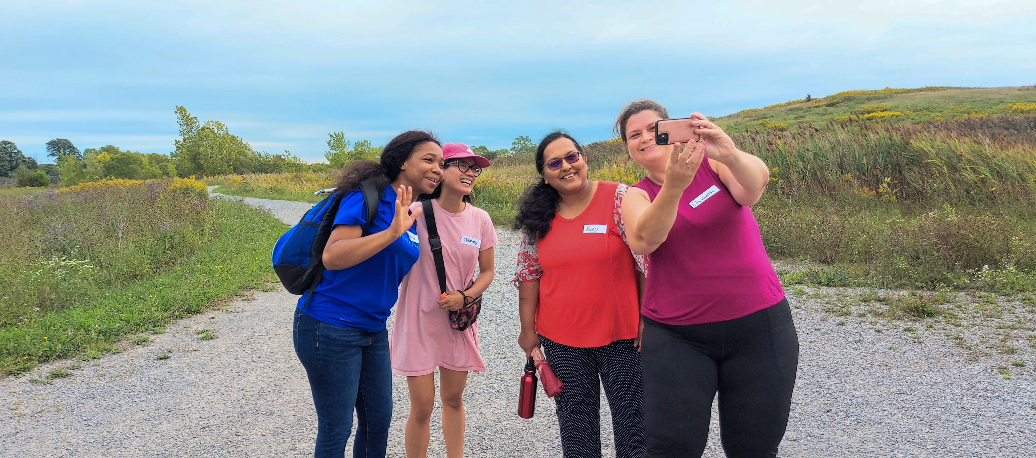Attendees pose for a selfie on a gravel walking trail during a guided parent and caregiver walk behi