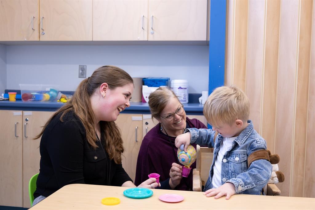 Two women interacting with young boy