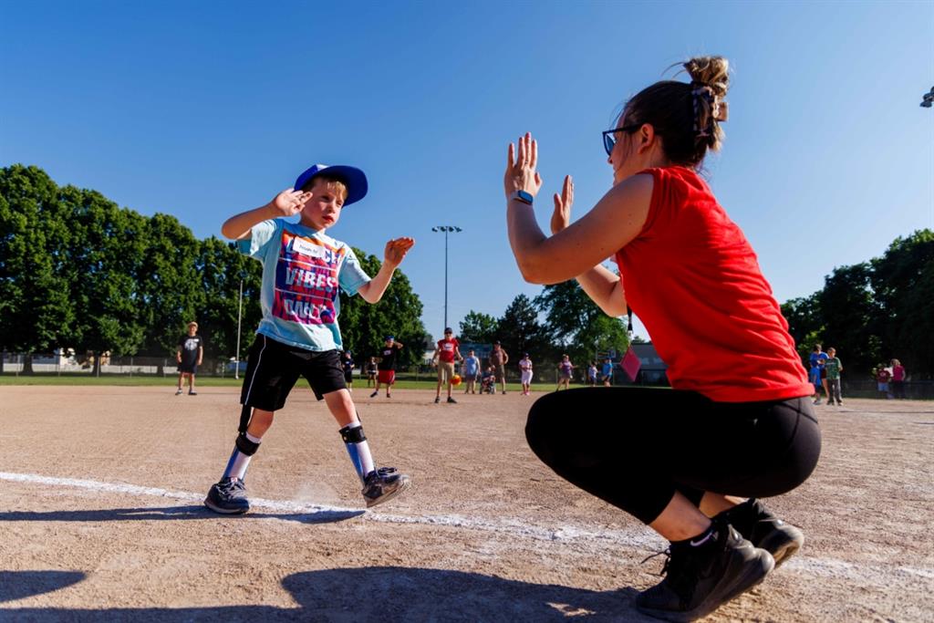 Women high fives boy on baseball diamond